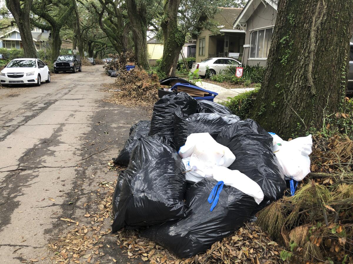 Bolsas y contenedores llenos de basura, así como pilas de escombros, en una calle de Nueva Orleans.
