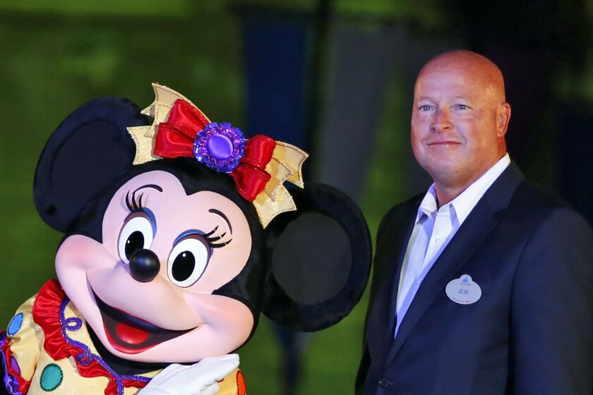 FILE - In this Sept. 11, 2015, file photo, Chairman of Walt Disney Parks and Resorts Bob Chapek poses with Minnie Mouse during a ceremony at the Hong Kong Disneyland, as they celebrate the Hong Kong Disneyland's 10th anniversary. The Walt Disney Co. has named Bob Chapek CEO, replacing Bob Iger, effective immediately, the company announced Tuesday, Feb. 25, 2020. (AP Photo/Kin Cheung, File)