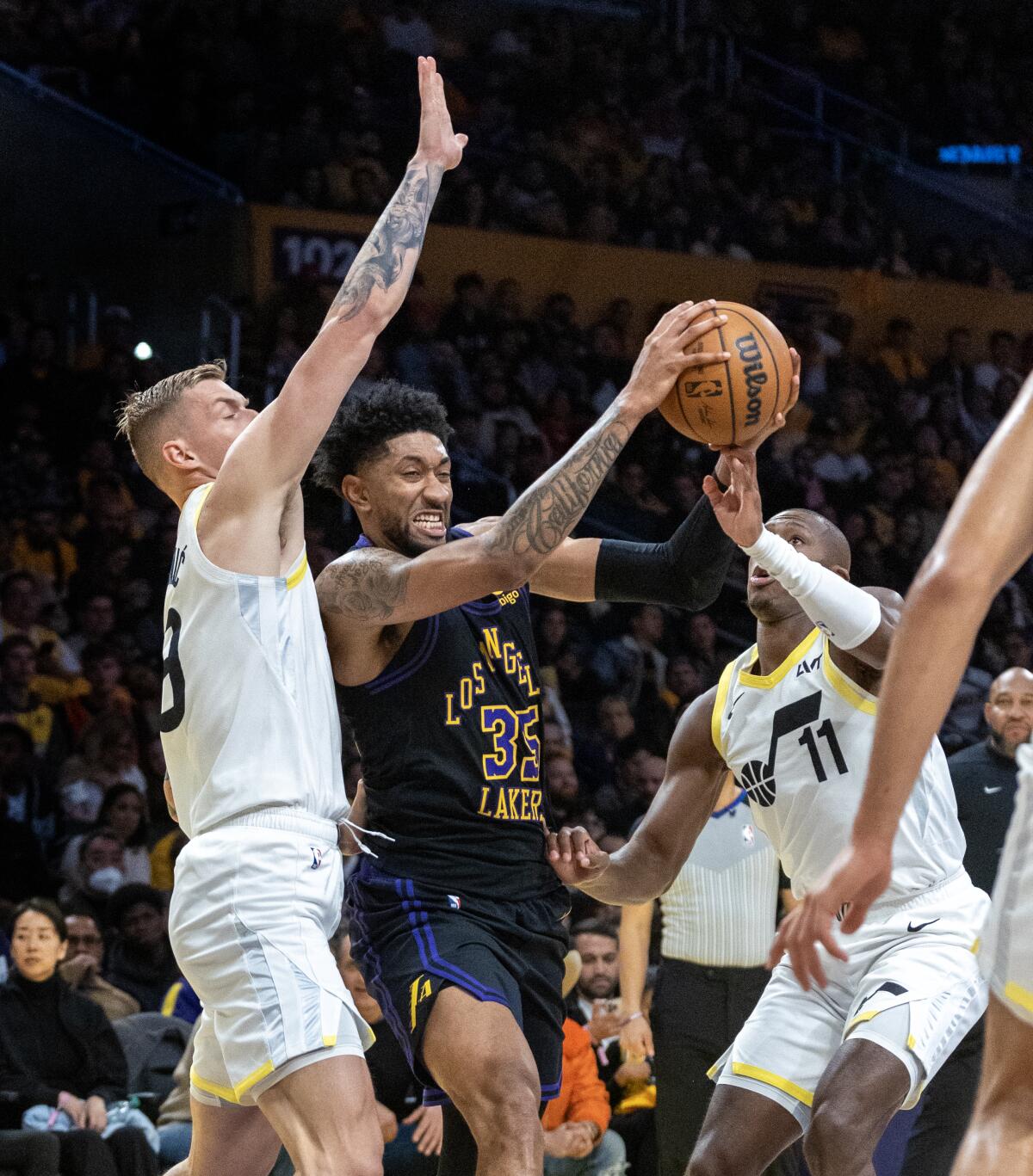 Lakers forward Christian Wood drives to the basket between Jazz forward Luka Samanic, left, and Jazz guard Kris Dunn, right.