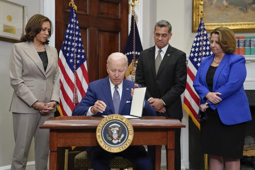 President Joe Biden signs an executive order on abortion access during an event in the Roosevelt Room of the White House, Friday, July 8, 2022, in Washington. From left, Vice President Kamala Harris, Health and Human Services Secretary Xavier Becerra, and Deputy Attorney General Lisa Monaco look on. (AP Photo/Evan Vucci)