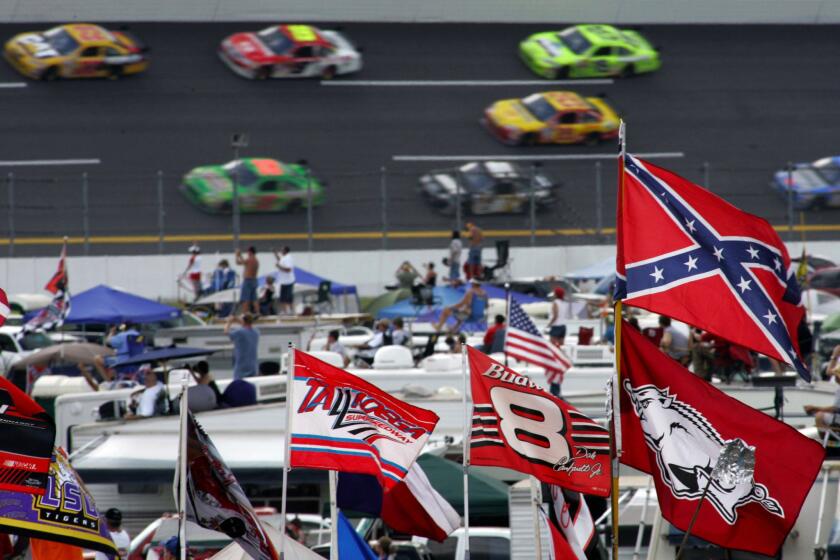 A Confederate flag flies in the infield as cars come out of a turn during a NASCAR race at Talladega Superspeedway on Oct. 7, 2007.
