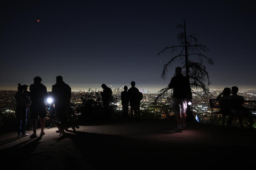 LOS ANGELES, CALIFORNIA - MAY 15: People take in the view from Griffith Park while a total lunar eclipse creates a "super blood moon" on May 15, 2022 in Los Angeles, California. The eclipse coincided with a super moon which occurs when the moon is at its closest point to earth. (Photo by Mario Tama/Getty Images)