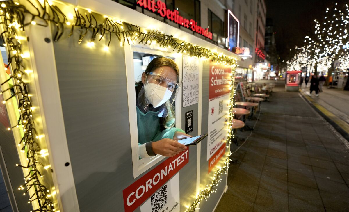 FILE - Coronavirus test center employee Denise waits for clients on the famous 'Kurfuerstendamm (Ku'damm)' shopping road in Berlin, Germany, on Dec. 21, 2021. The risk of recession is looming for Germany after Europe’s biggest economy shrank at the end of 2021 and as it faces a bumpy start to this year. The rapid spread of COVID-19's omicron variant is deterring people from shopping and travel and supply bottlenecks are holding back manufacturers. The state statistics agency said Friday, Jan. 14, 2022 that output in Germany fell by between 0.5% and 1% in the fourth quarter. (AP Photo/Michael Sohn, File)