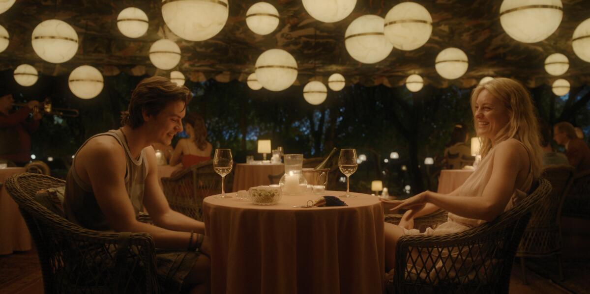 A man and a woman sit across from each other at a dining table with wine glasses.