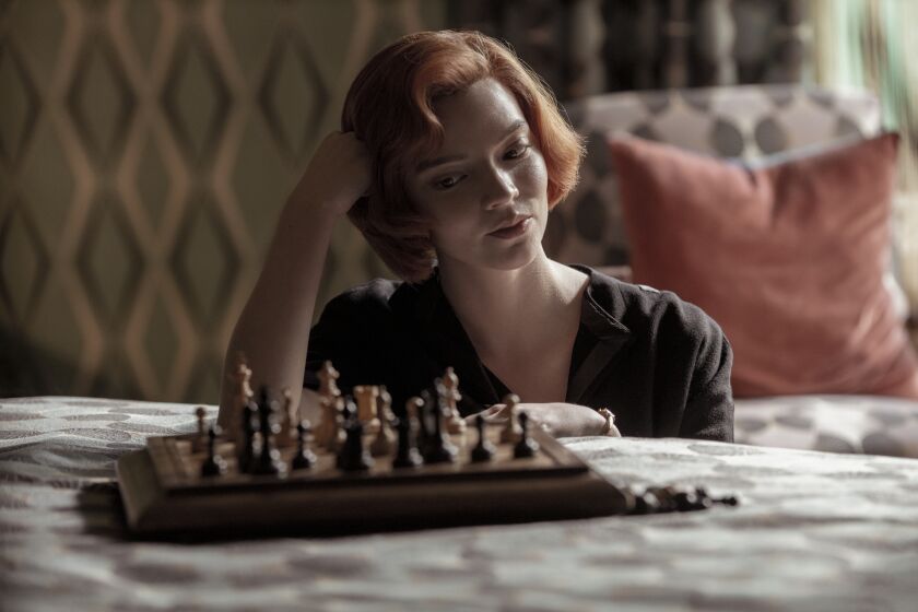 A woman looking at a chess board on a bed