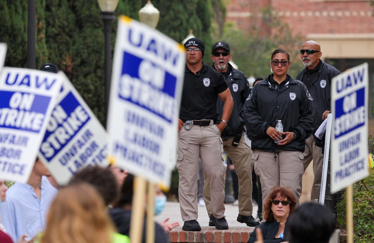 Security personnel watch as members of United Auto Workers Local 4811strike at UCLA on May 28. 