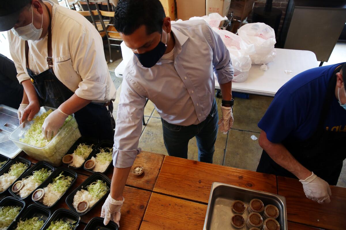 People in face masks and gloves set out food at a restaurant.