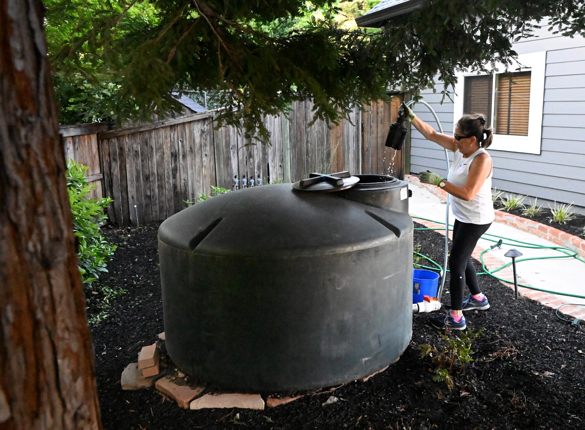 Anne Friedemann adjusts a pump at her recycled water tank at her home in Healdsburg.
