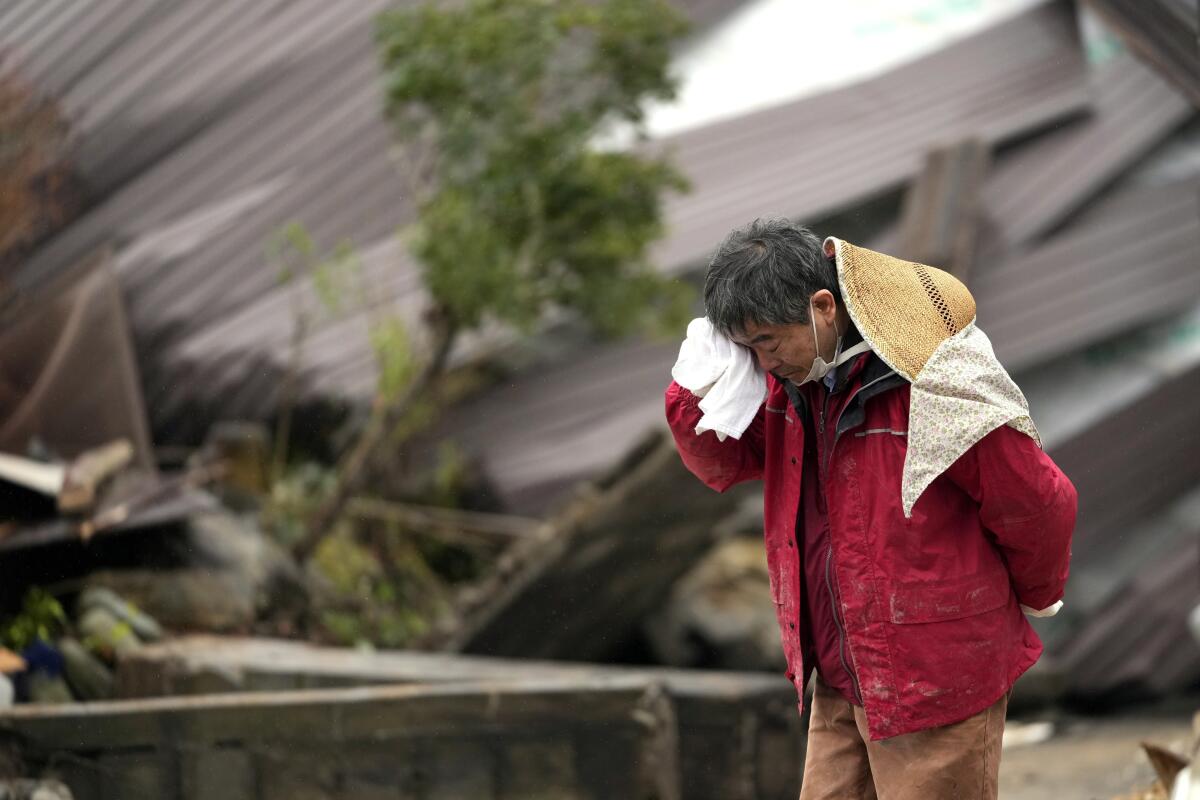 Un hombre llora mientras encuentran los restos de un familiar entre los restos de una vivienda 