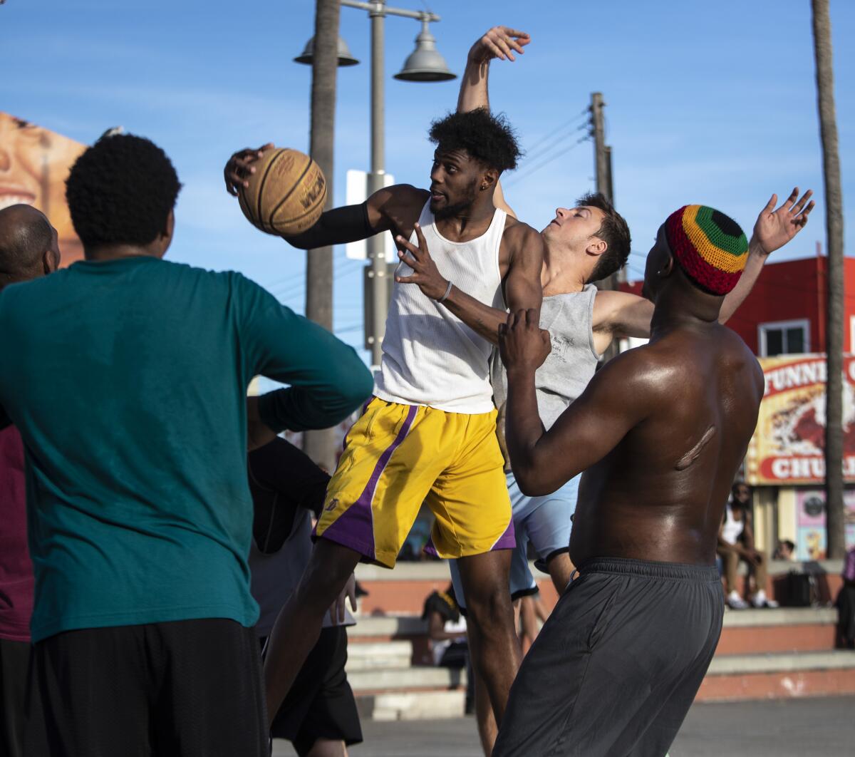 John Lackey, 20, of Long Beach, comes down with a rebound during a pickup game on Friday in Venice Beach.