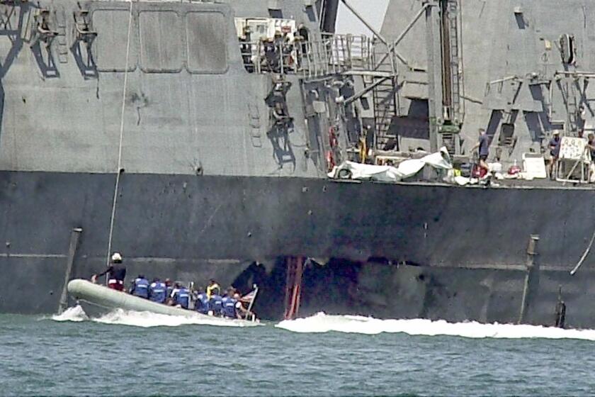 Investigators in a boat examine the hull of the USS Cole at the Yemeni port of Aden on Sunday, Oct. 15, 2000.