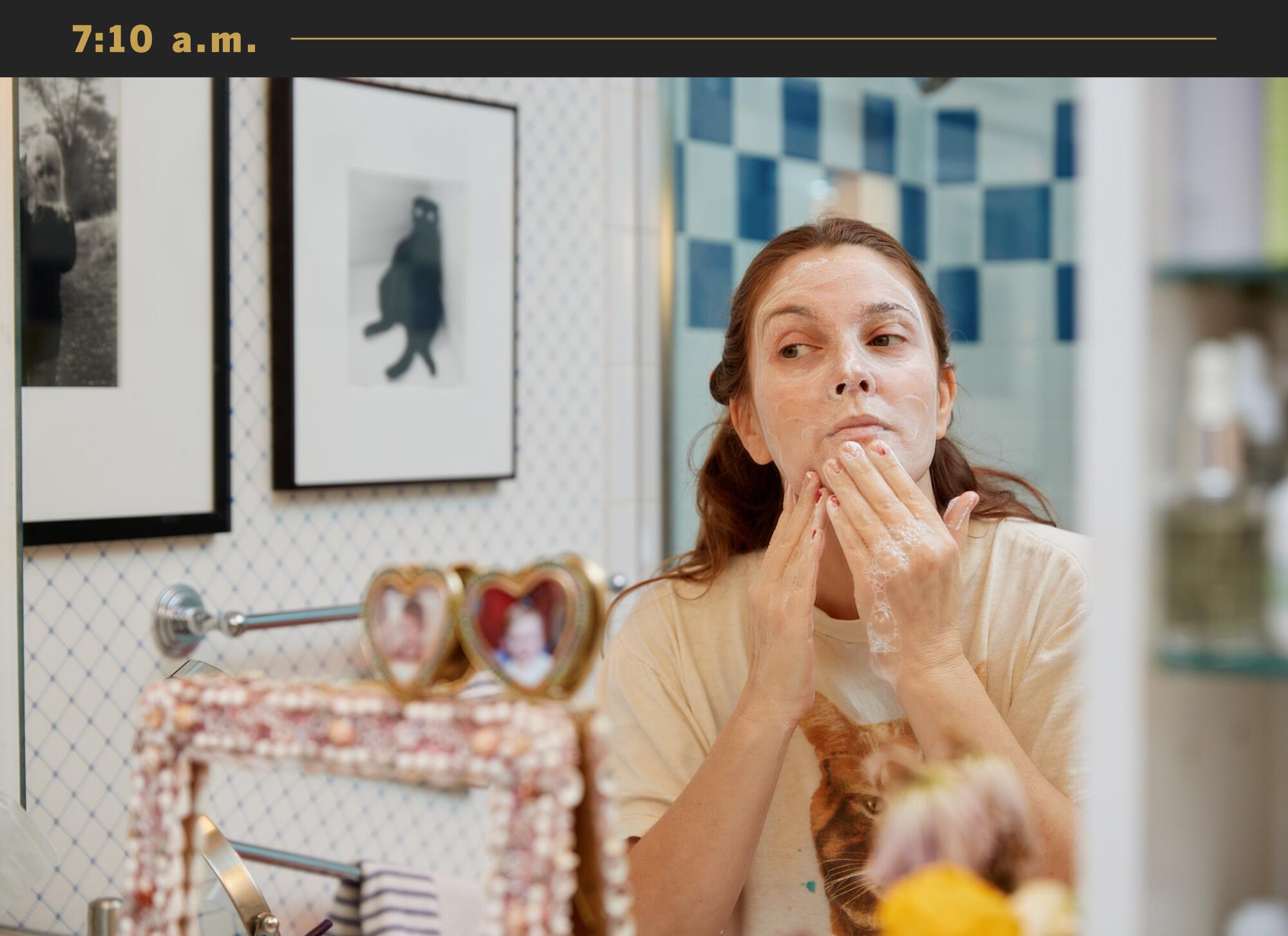Drew Barrymore looks in her bathroom mirror while washing her face.