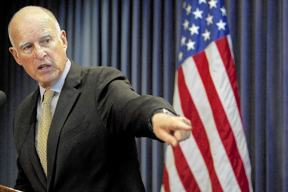 Gov. Jerry Brown points to a poster showing elements of his proposed budget for 2014-15. Brown faces a challenge with both Democrats and Republicans in finding funding for his $68-billion bullet train project.