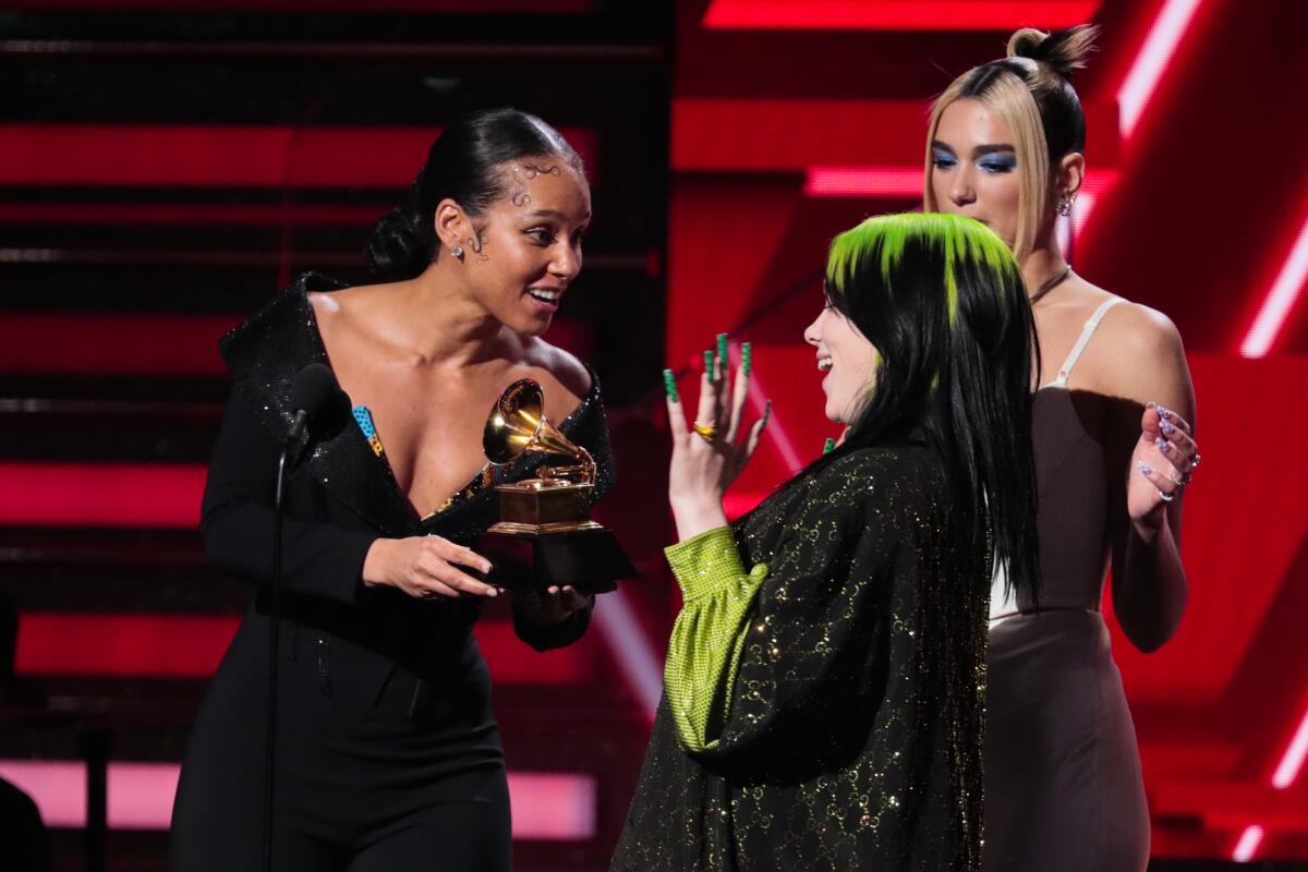 Alicia Keys and Dua Lipa present Billie Eilish an award on stage at the 62nd Grammy Awards.