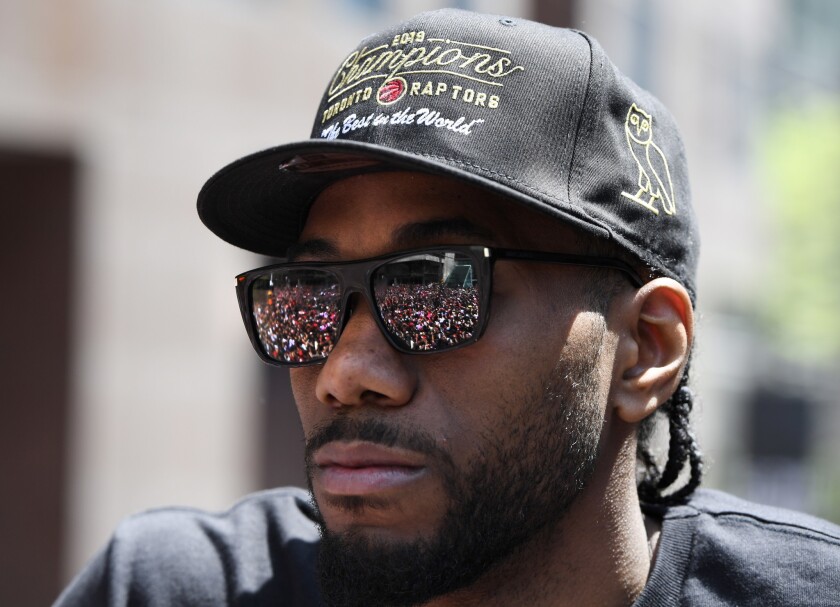 The real Kawhi Leonard takes in the Toronto Raptors' NBA championship parade from the top of a double-decker bus. Meanwhile, an impostor roamed the crowd signing autographs and posing for selfies with fans.