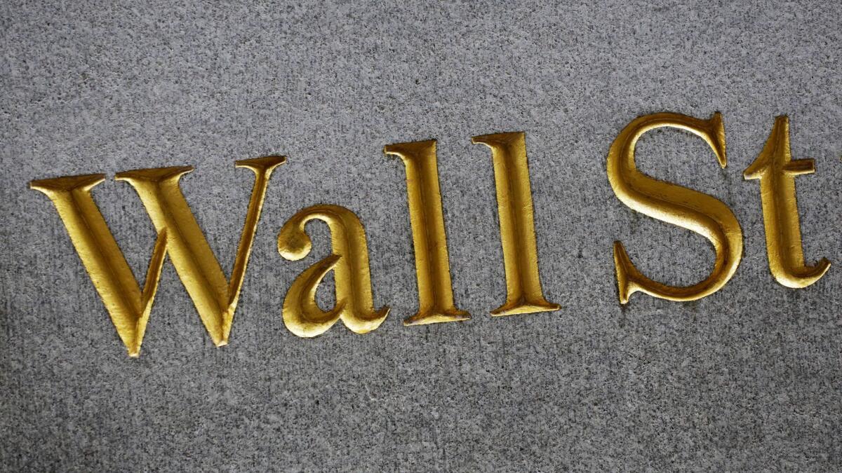"Wall St" engraved on a building in New York.