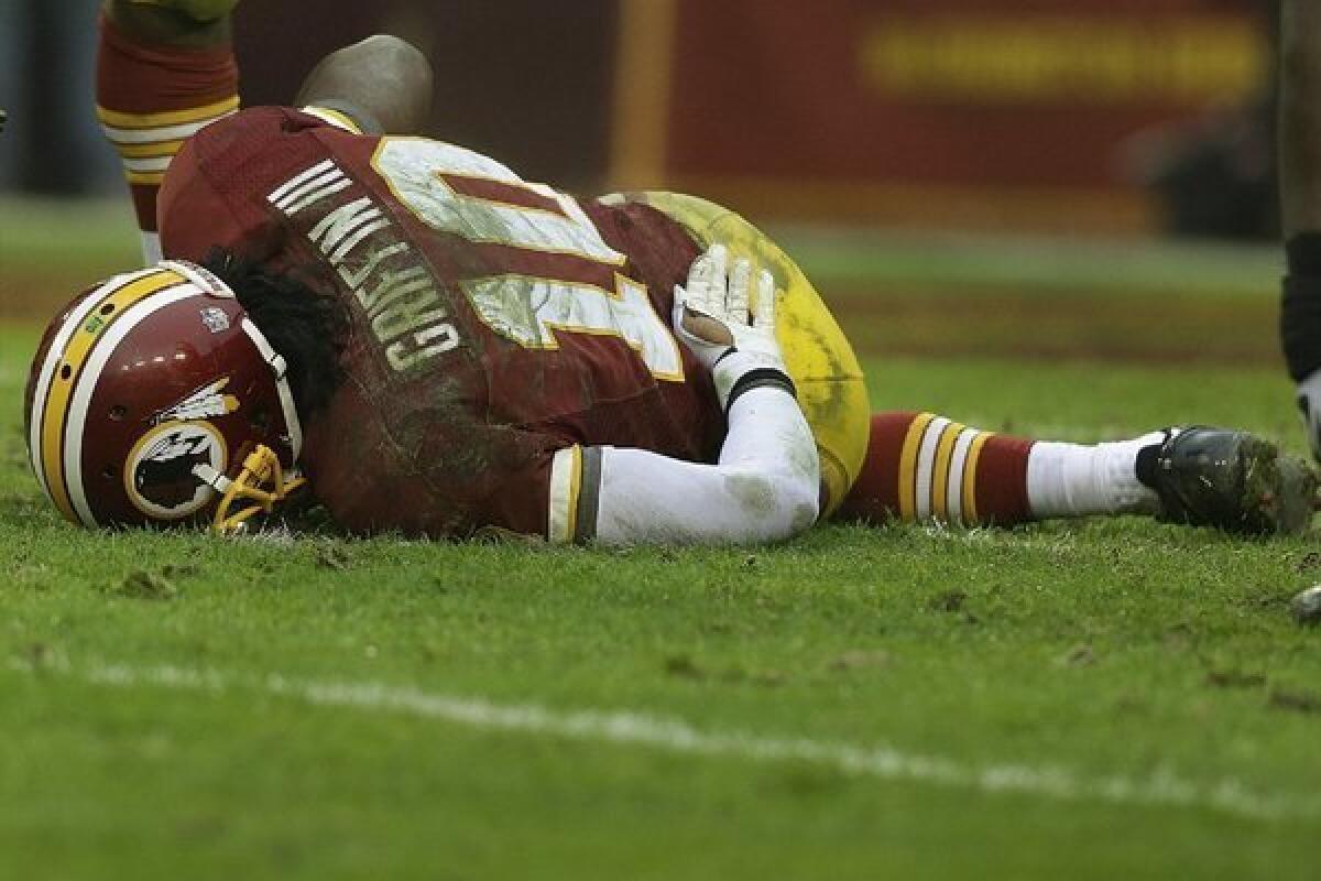 Washington Redskins quarterback Robert Griffin III is on the ground after a sack by Baltimore Ravens defensive end Arthur Jones.