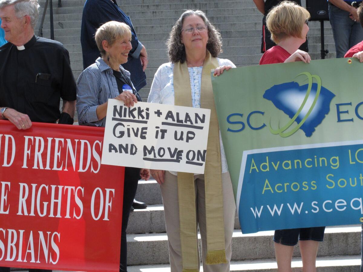 Gloria Talcove-Woodward, left, and Holli Emore, right, hold up a sign asking South Carolina Gov. Nikki Haley and Atty. Gen. Alan Wilson to stop fighting for the state's gay marriage ban.