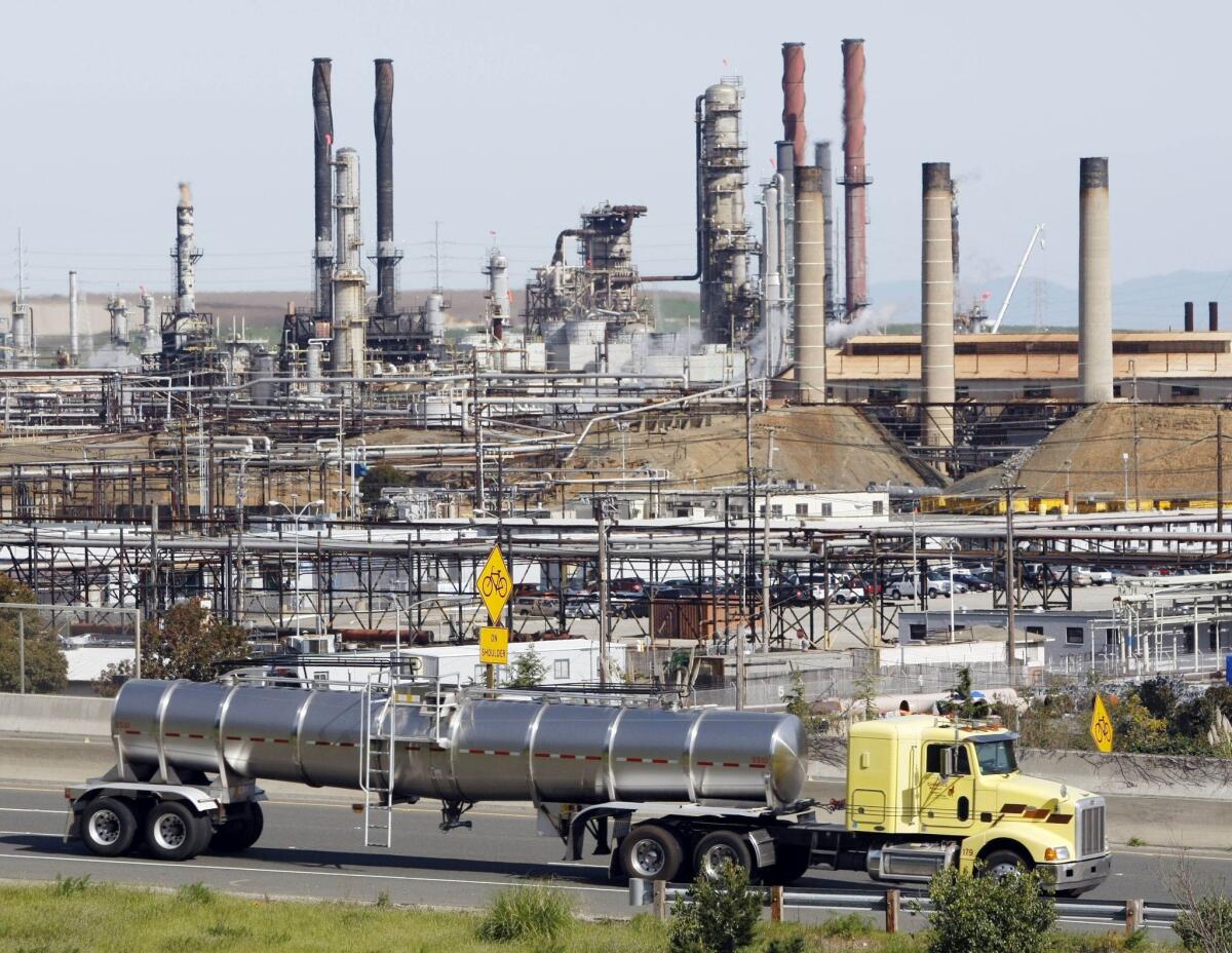 A tanker truck passes the Chevron oil refinery in Richmond, Calif. A decline in oil refining added to overall declines in factory output in September, the Federal Reserve said.