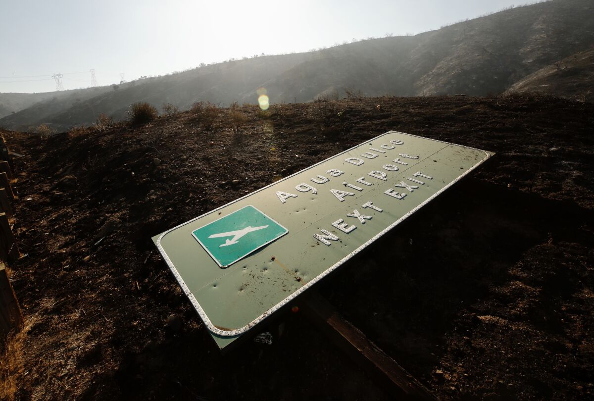 A sign for Agua Dulce Airport lies next to the 14 Freeway near the scene of the Soledad fire.