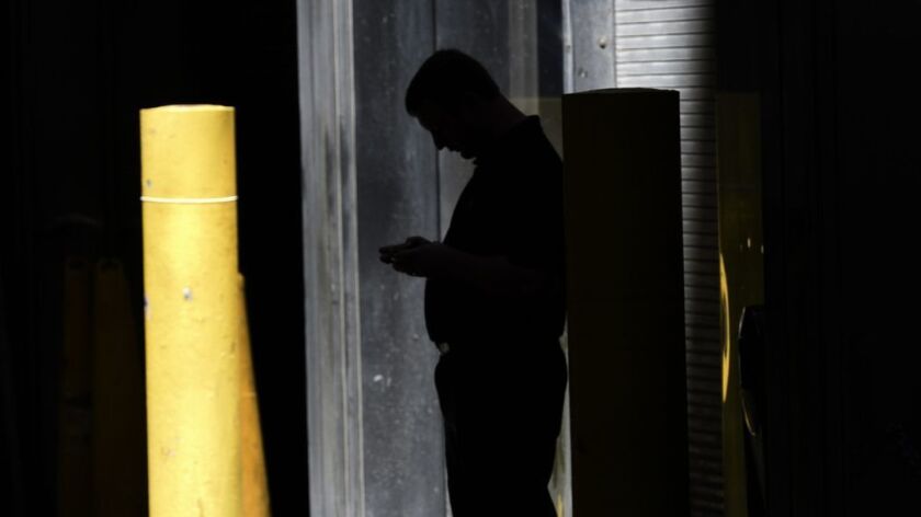 A man checks his phone in an alley.