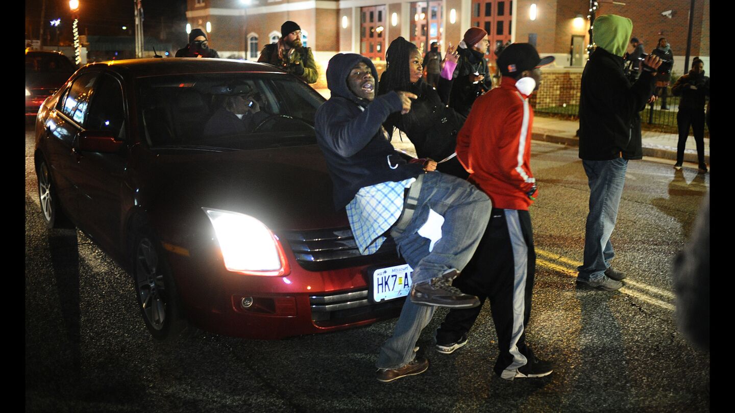 A protester prevents a female driver from driving along South Florissant Road outside the Ferguson police station during a demonstration in Missouri on Nov. 20.