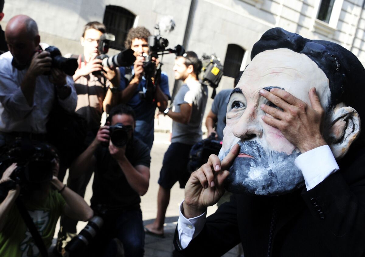 A demonstrator wearing a mask depicting Spanish Prime Minister Mariano Rajoy protests outside the court in Madrid where the ruling Popular Party's former treasurer was testifying about allegations of a slush fund.