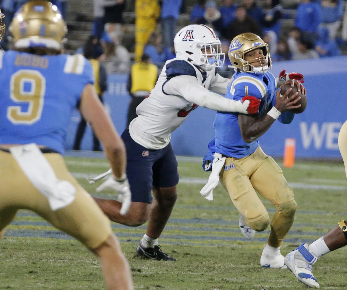 UCLA quarterback Dorian Thompson-Robinson gets pulled down for a loss by Arizona defensive back Hunter Echols.