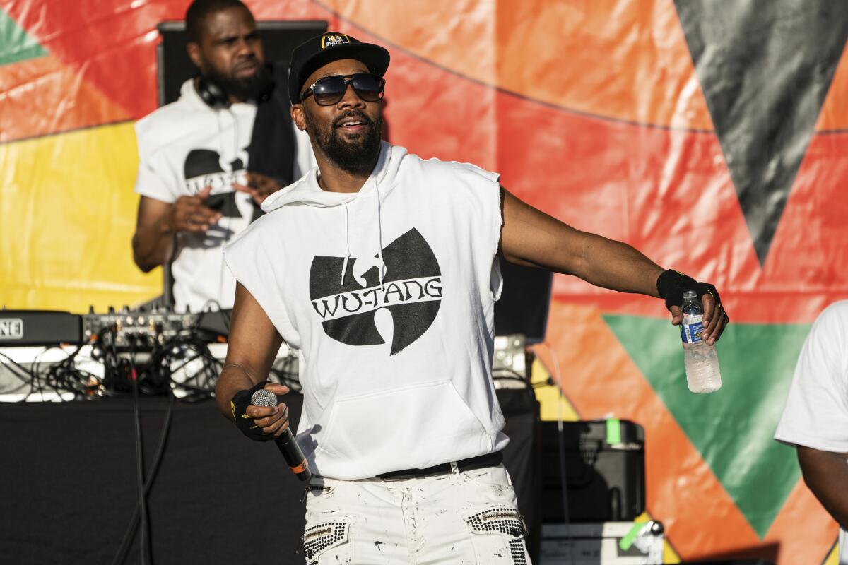 RZA of Wu-Tang Clan wears a sleeveless white hoodie that has a black Wu-Tang symbol  onstage