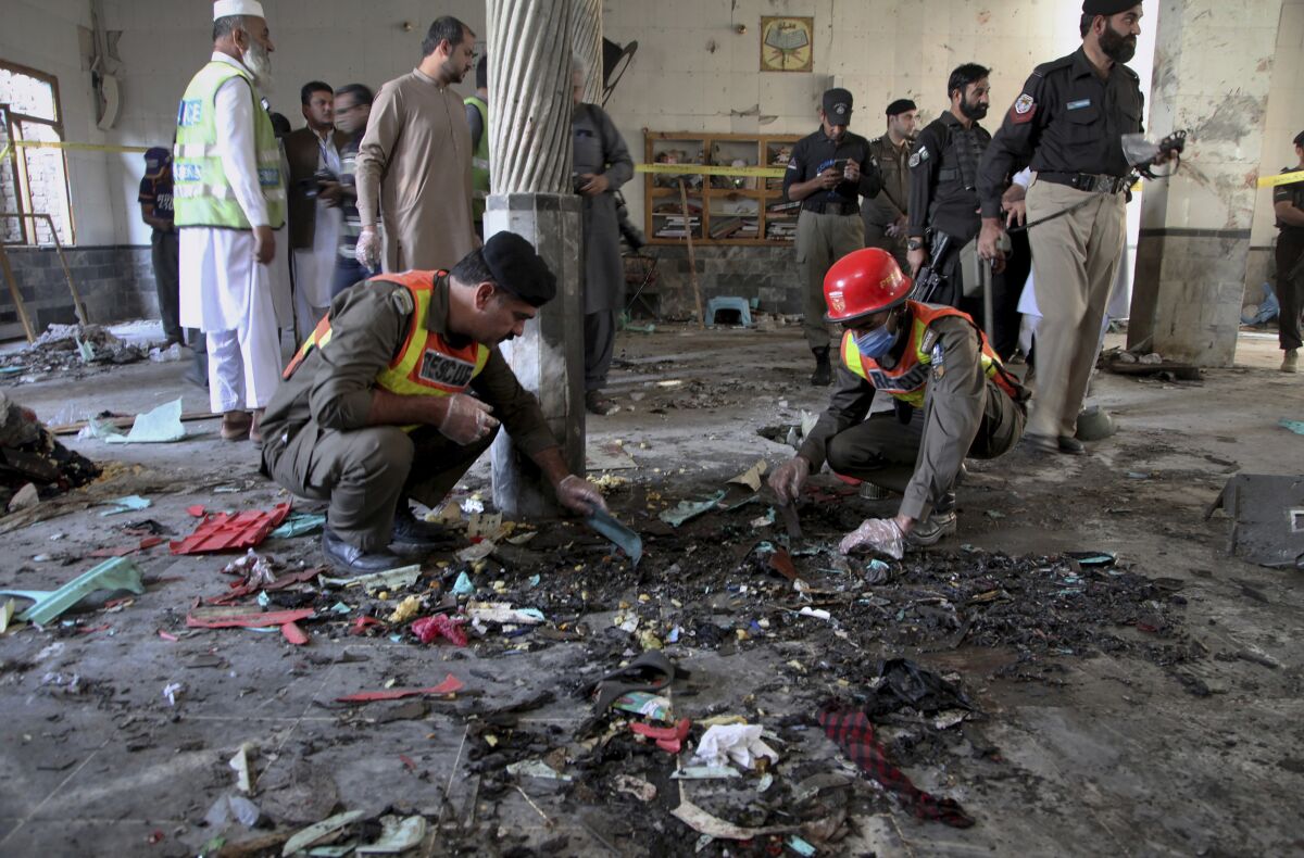 Rescue workers and police officers examine an Islamic school in Peshawar, Pakistan, that was hit by a powerful bomb Tuesday.
