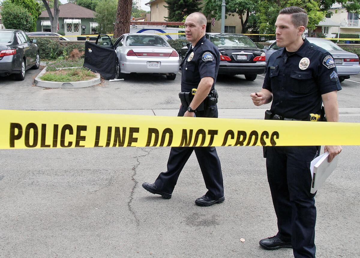 Burbank police officers investigate the scene where a dead body was found in a parked car in the Buena Vista Library parking lot on Friday, Aug. 7, 2015.