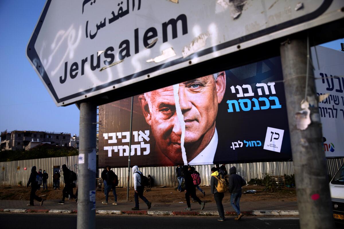 Palestinian laborers walk past an election campaign billboard