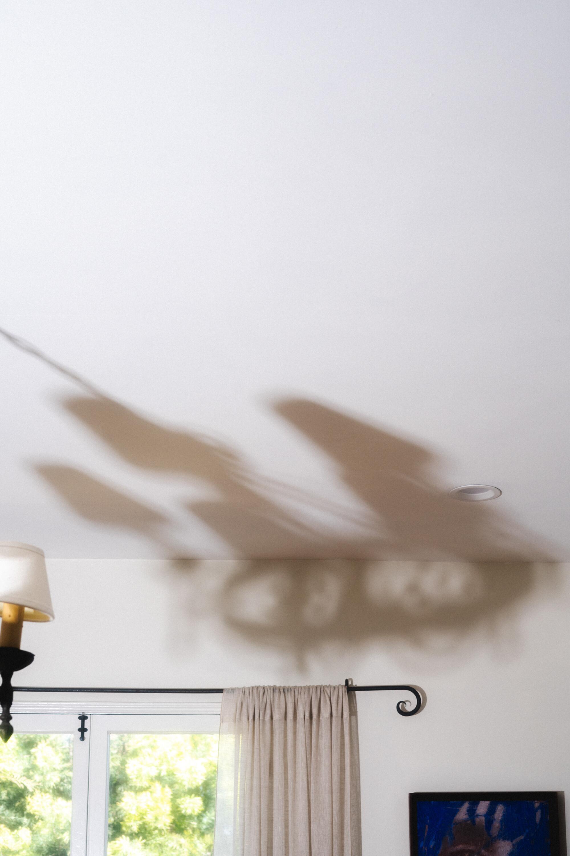 A picture of a ceiling with the large shadow of a hanging lamp.