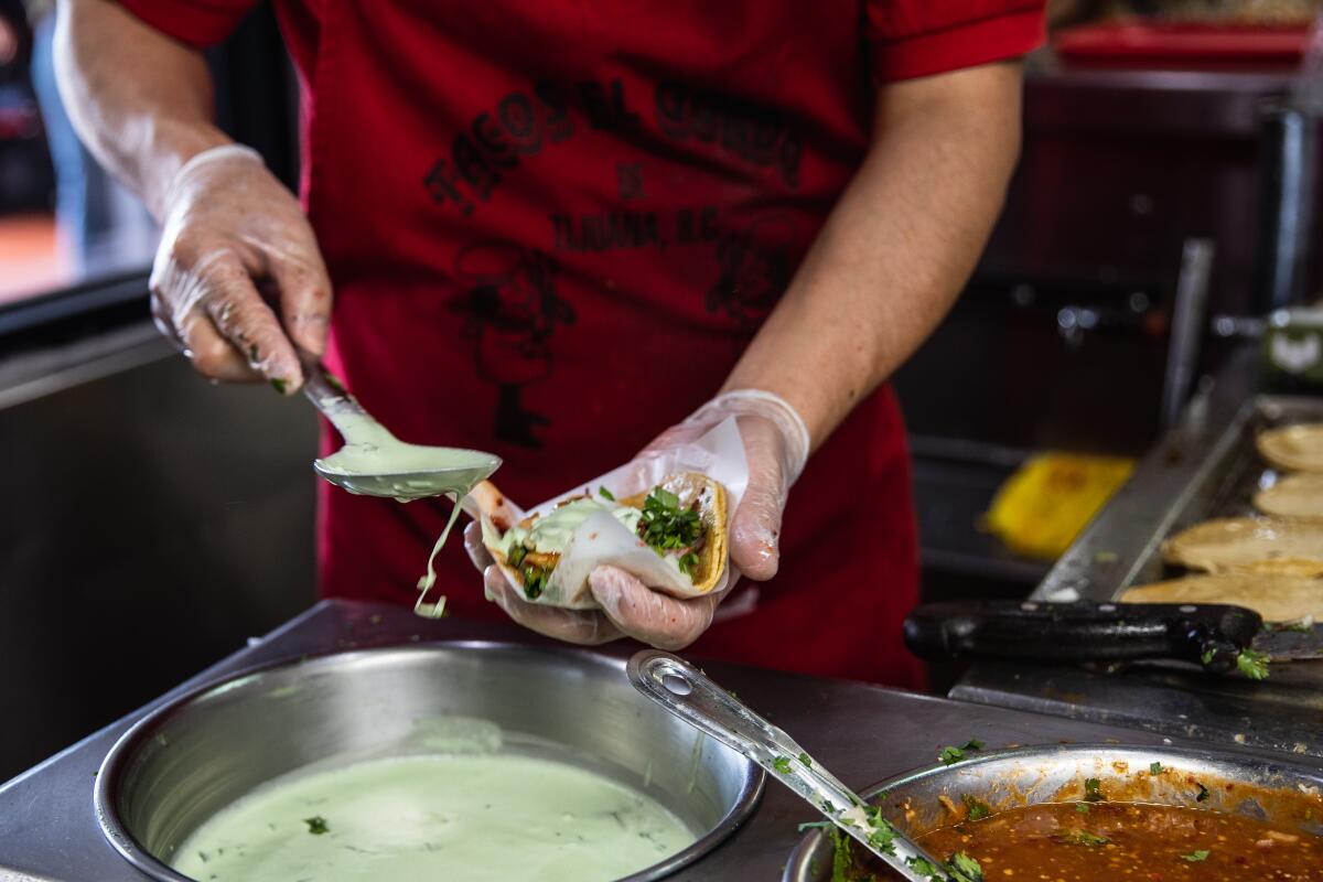 Agustín Pérez Olmos prepara tacos de adobada durante la hora del almuerzo en Tacos El Gordo