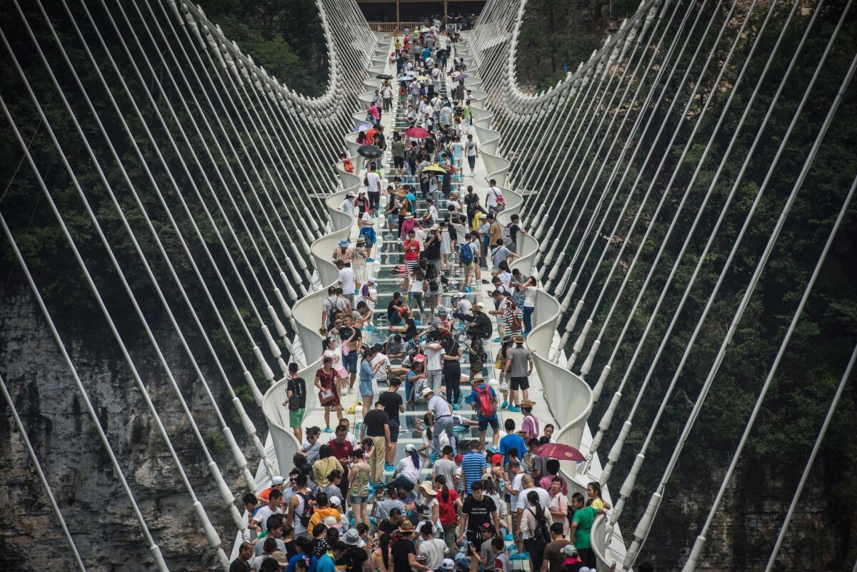 Visitors cross the world's highest and longest glass-bottomed bridge above a valley in Zhangjiajie in China's Hunan province the day after its Aug. 20 opening.