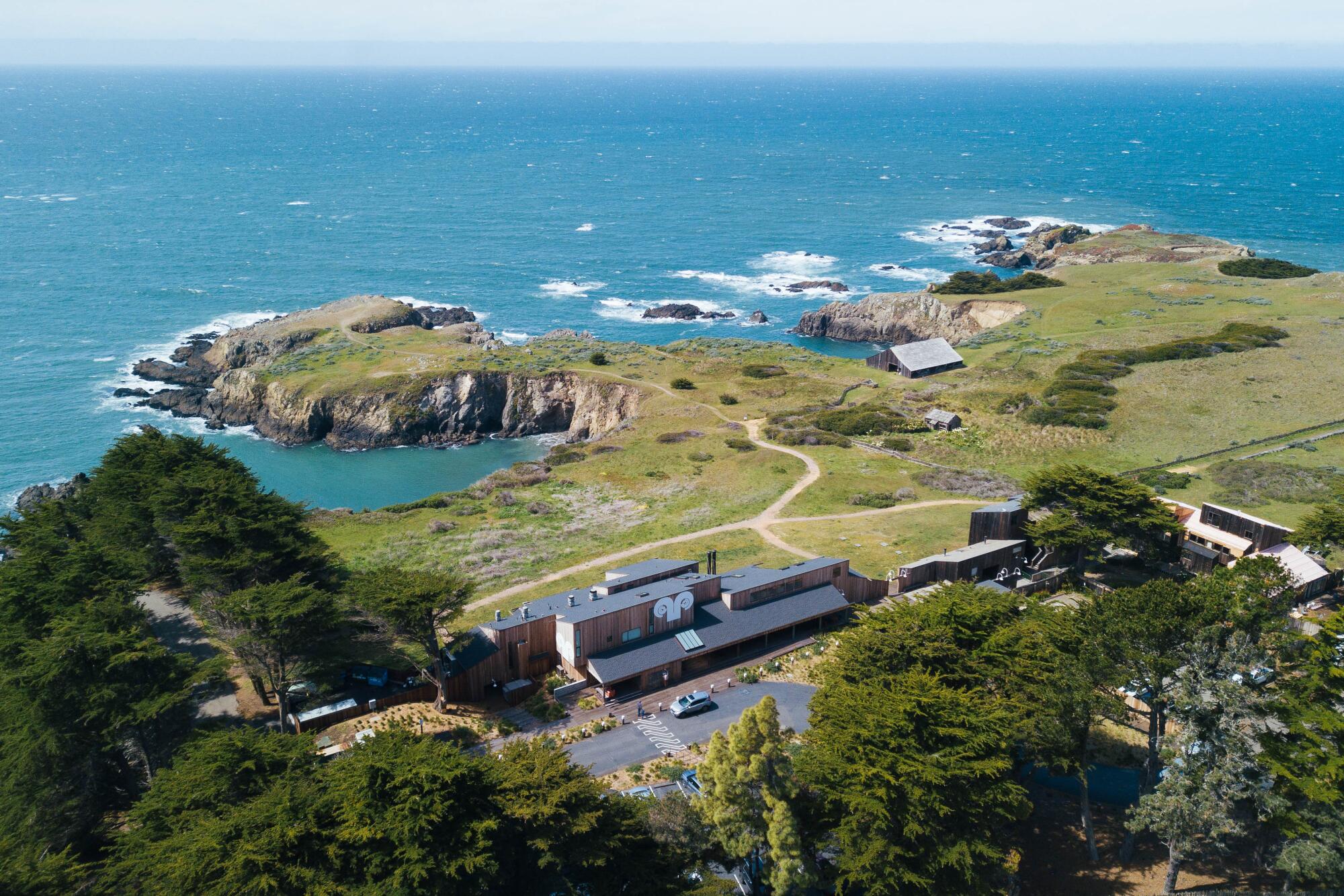 A view of a building sitting just inland from coastal headlands in the Pacific Ocean.