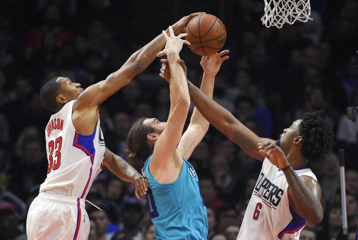 Clippers forward Wesley Johnson, left, and center DeAndre Jordan (6) reach for a rebound along with Hornets forward Spencer Hawes during the first half.