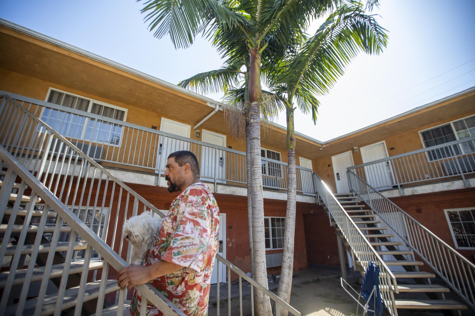 A man carries his dog outside a motel