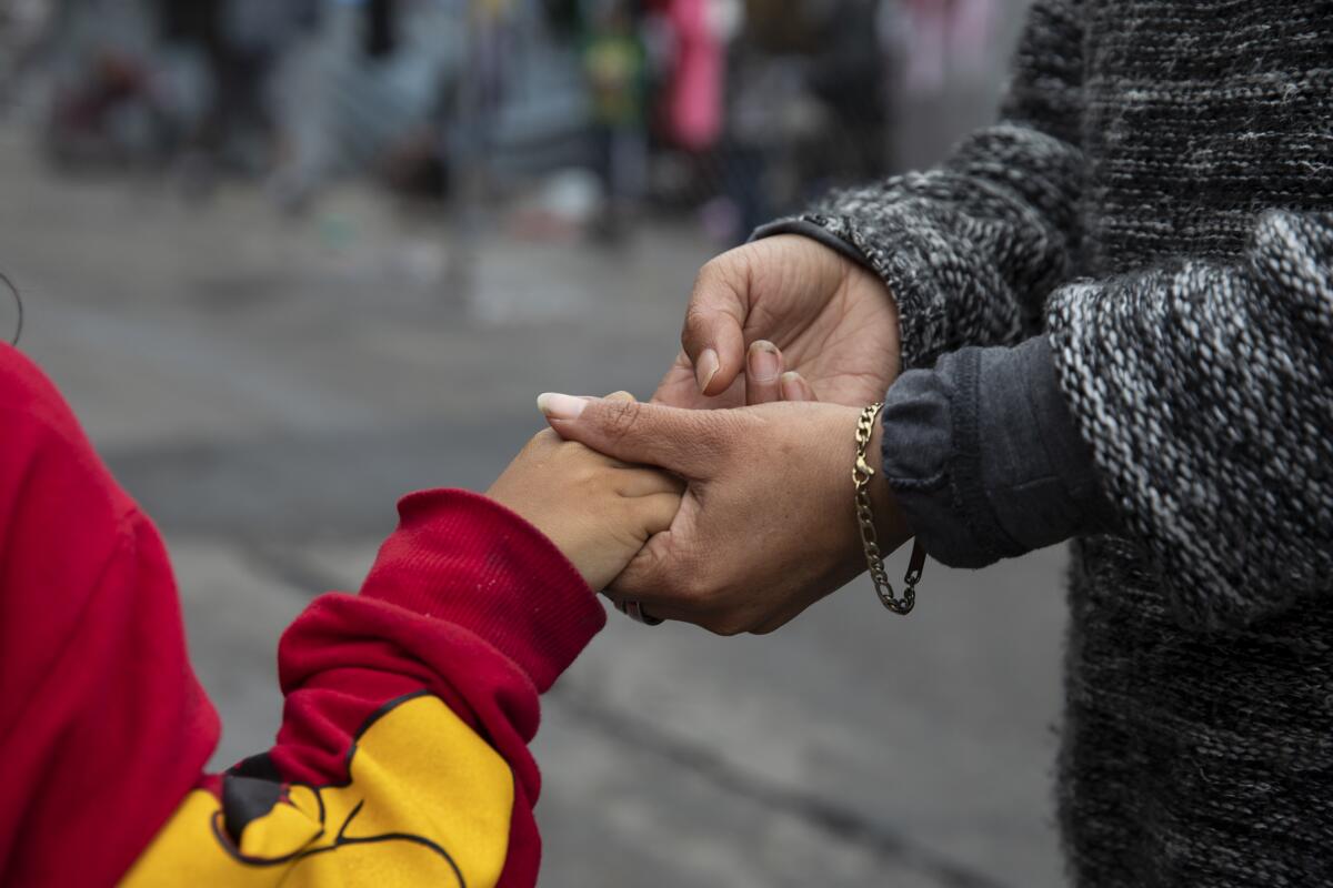 Maria holds her daughter Evelyn's hand 