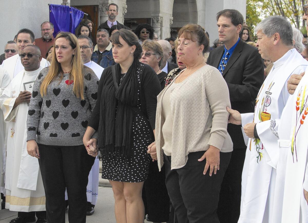 Tina Meins, left, and Tawnya Meins, center, stand with mother Trenna Meins, right, as the casket of their father, San Bernardino shooting victim Damian Meins, is placed in the hearse at St. Catherine of Alexandria Church in Riverside.