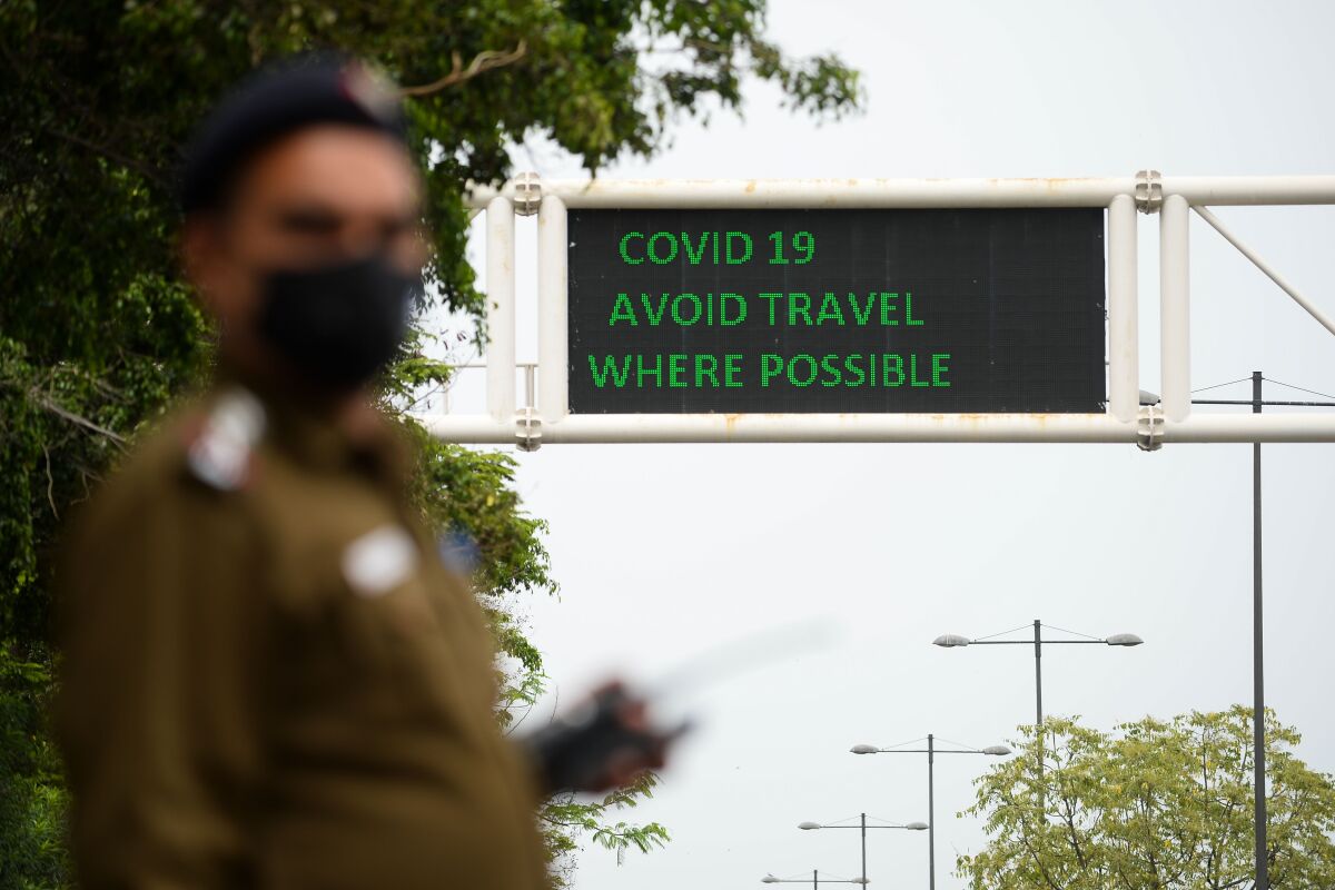 A policeman wearing a mask stands along a road in New Delhi, India.
