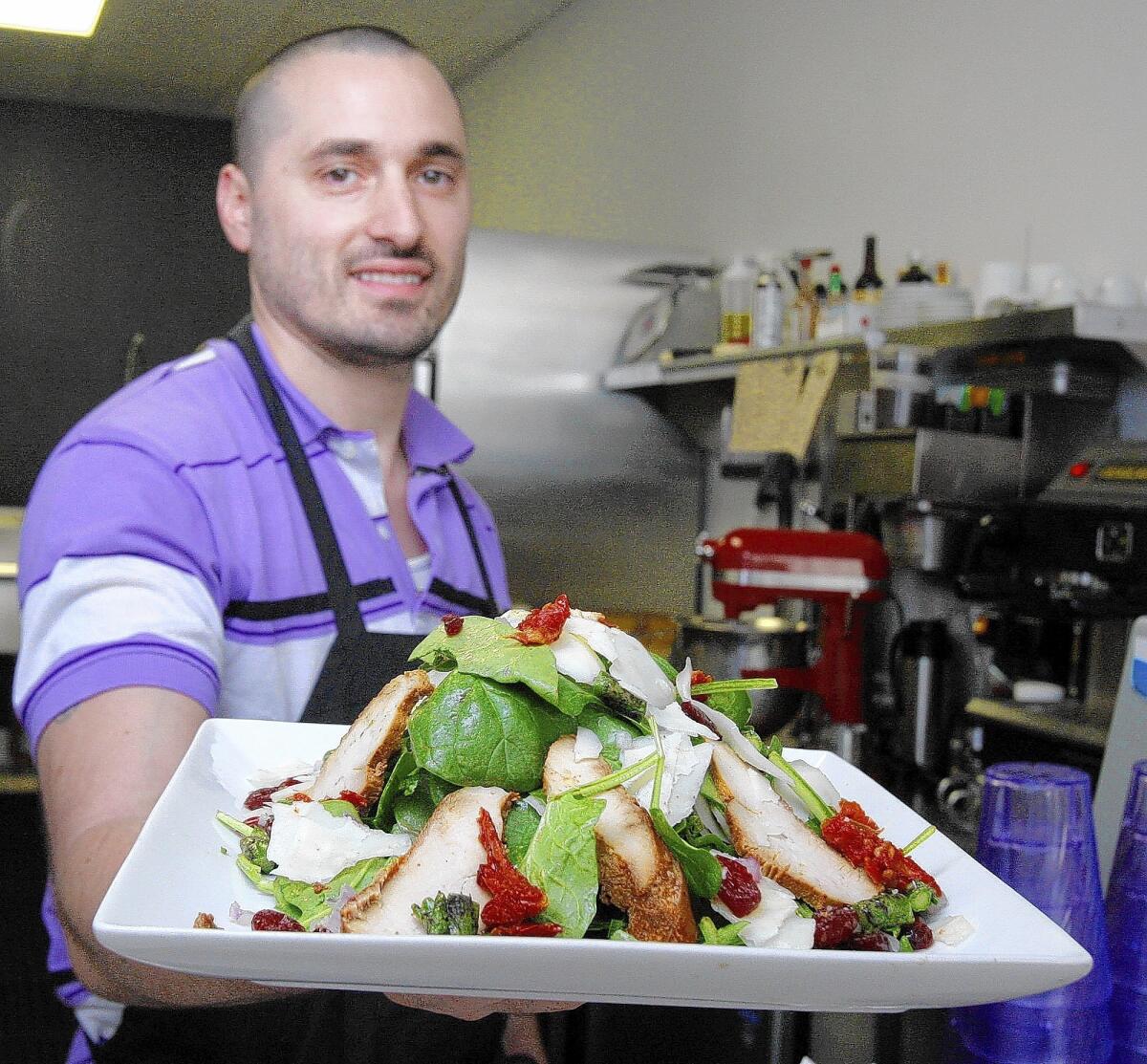 Chef Aurelien (Tony) Mosconi holds a La Chicken Manchego Salad with spinach, grilled chicken, imported Manchego cheese, red onions, cranberries, sundried tomatoes, asparagus, homemade raspberry vinaigrette at Monsieur Crêpe in Sierra Madre on Friday, March 7, 2014.