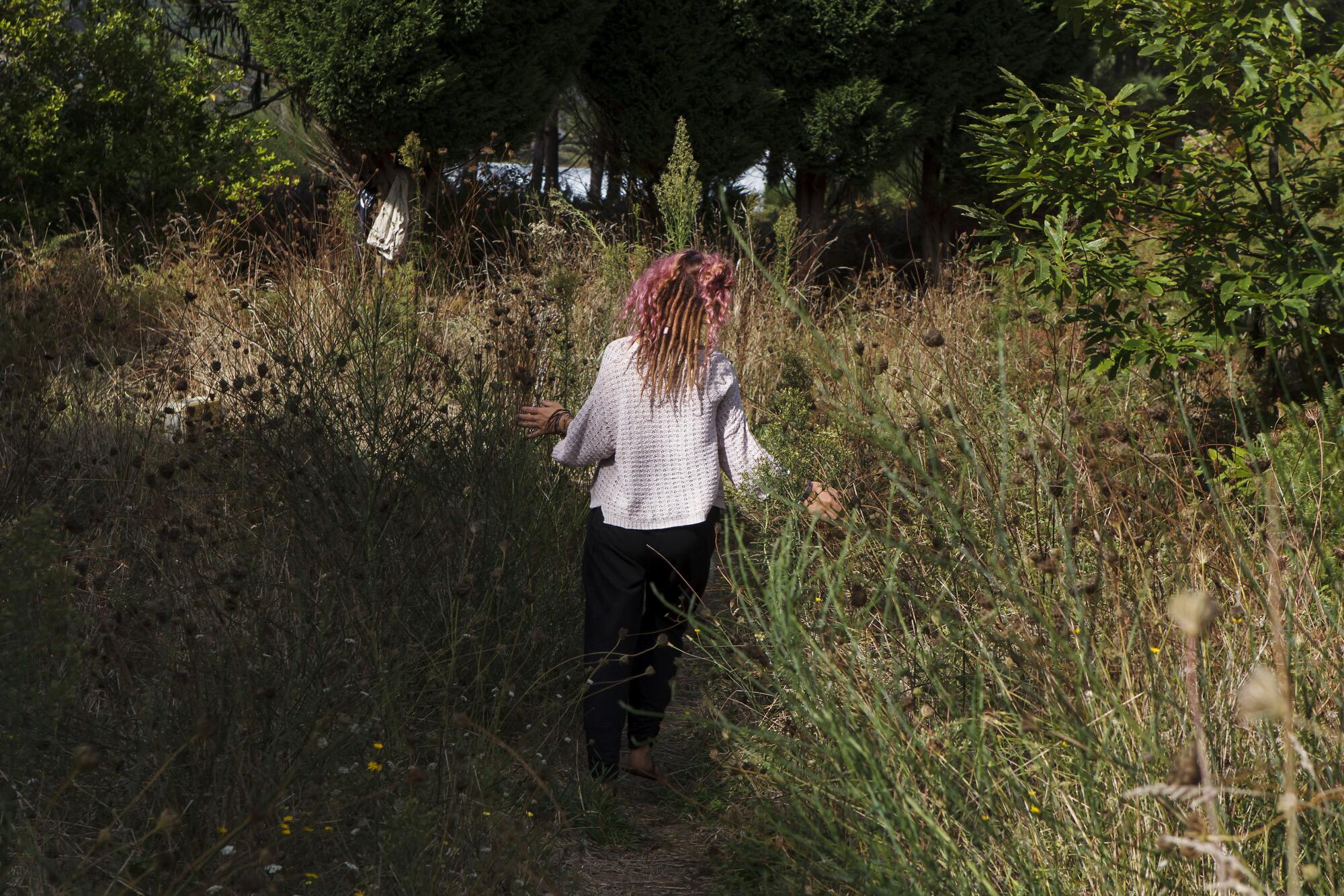 Momo Gruss, from her back, in the forest where she spent the summer living in a cabin she built.