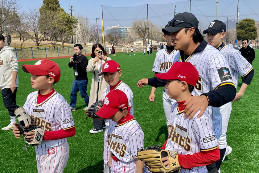 Padres' star Ha-Seong Kim escorts kids Saturday during a youth clinic at Yongsan Children's Park in Seoul, South Korea.