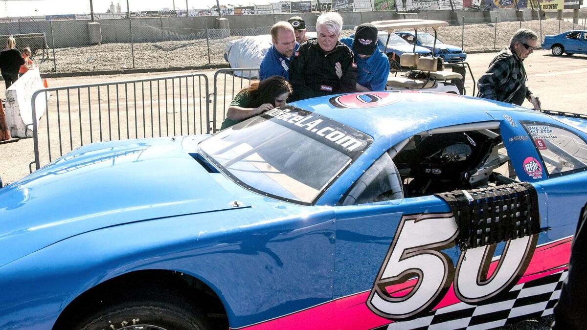 Michael Long was helped into the stock car he rode in Sunday by Belmont Village Senior Living caregiver Anaees Khacikyan, left, driver Matt Petrie and Irwindale Speedway owner Tim Huddleston.