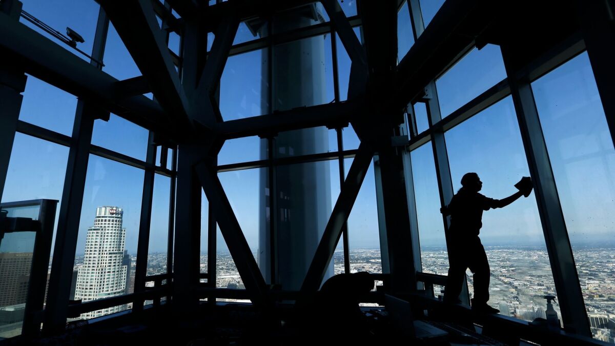 Pablo Peralta cleans the windows at the base of the sail on the 73rd story on opening day of the Wilshire Grand Center.