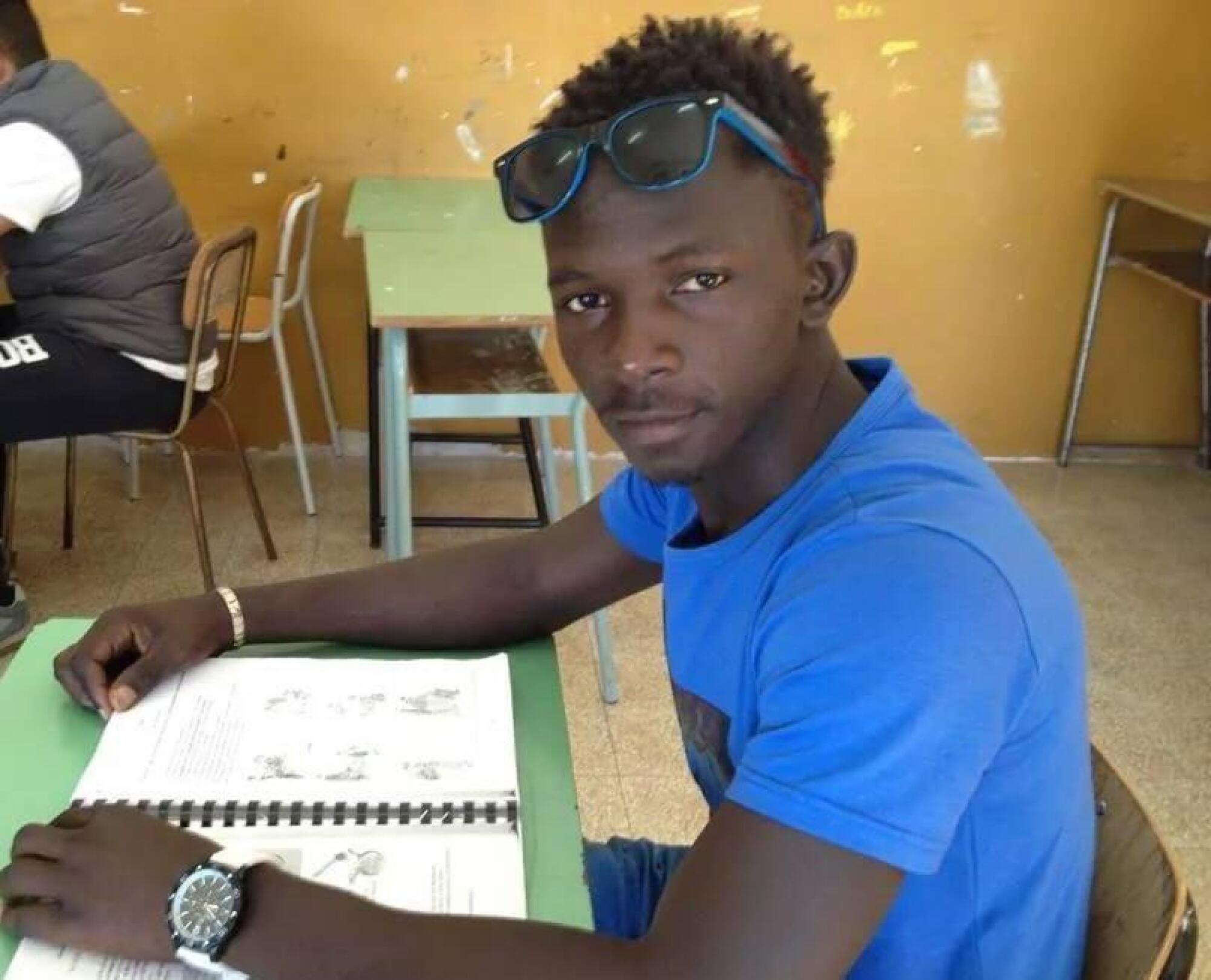 A young man from Senegal sits at a desk.