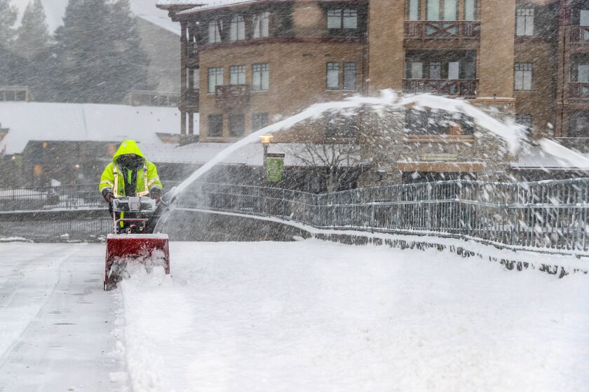 A worker clears snow from the Palisades Tahoe ski area near Lake Tahoe, where a winter storm hit the Sierra Nevada overnight and will continue pounding the region throughout Thursday, bringing heavy mountain snow.