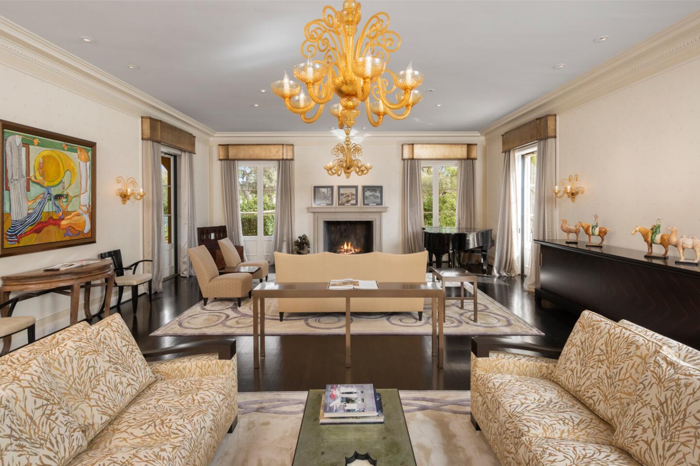 A rectangular room with two sitting areas, a fireplace and a chandelier.