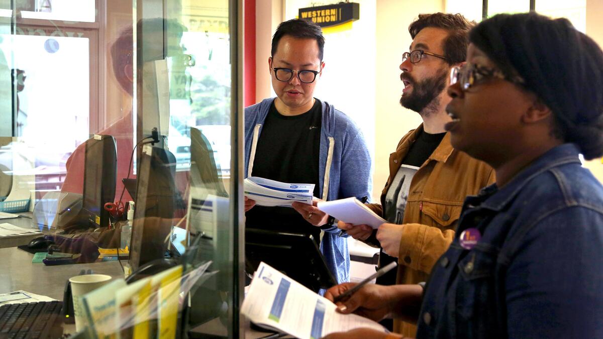 Ray Chay, left, director of operations at a high-interest consumer lending company, L.A. Times staff writer James Rufus Koren and Sybil Mulokwa, a manager at a company that develops software for small banks and credit unions do transactions at a Money Mart in Hollywood.